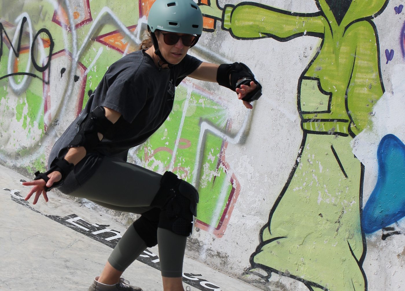 A rider low in a carve on the transition of a graffitied concrete bowl