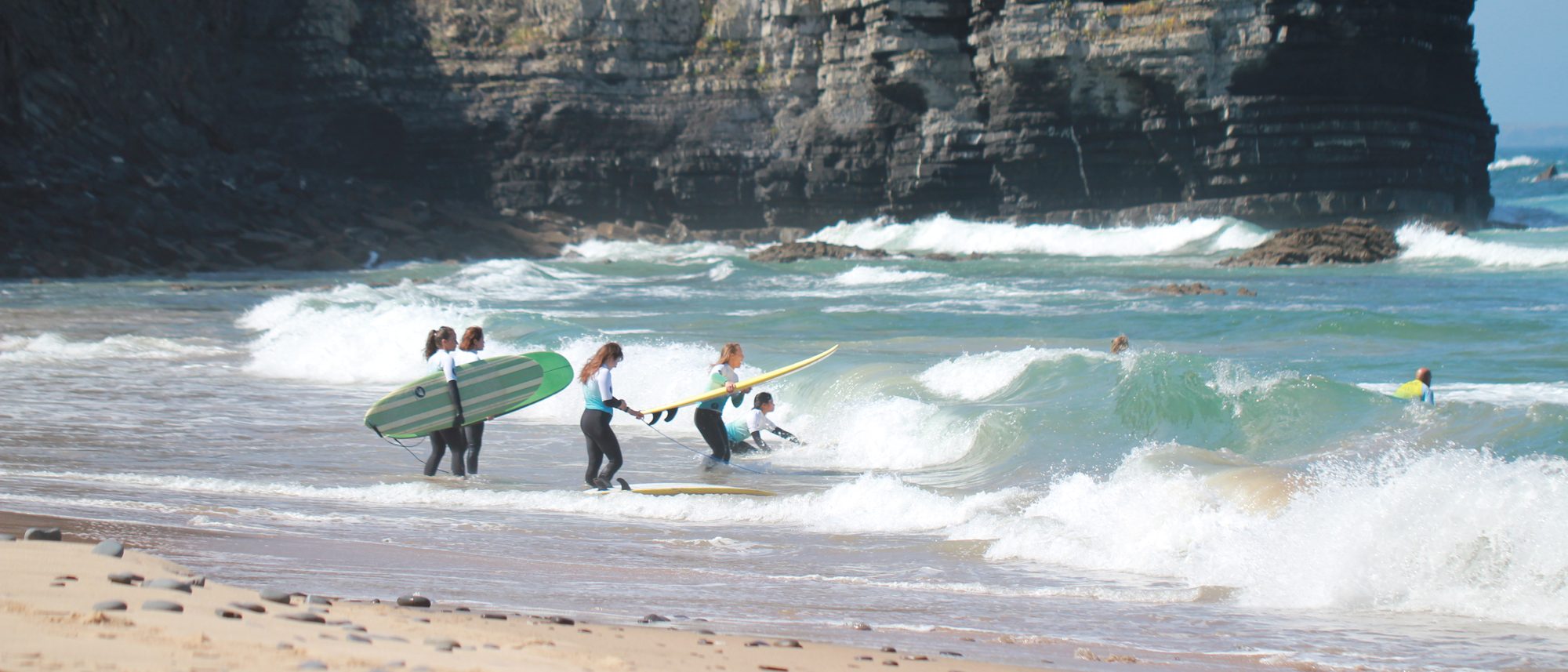 A coached group walking into the water below the cliffs