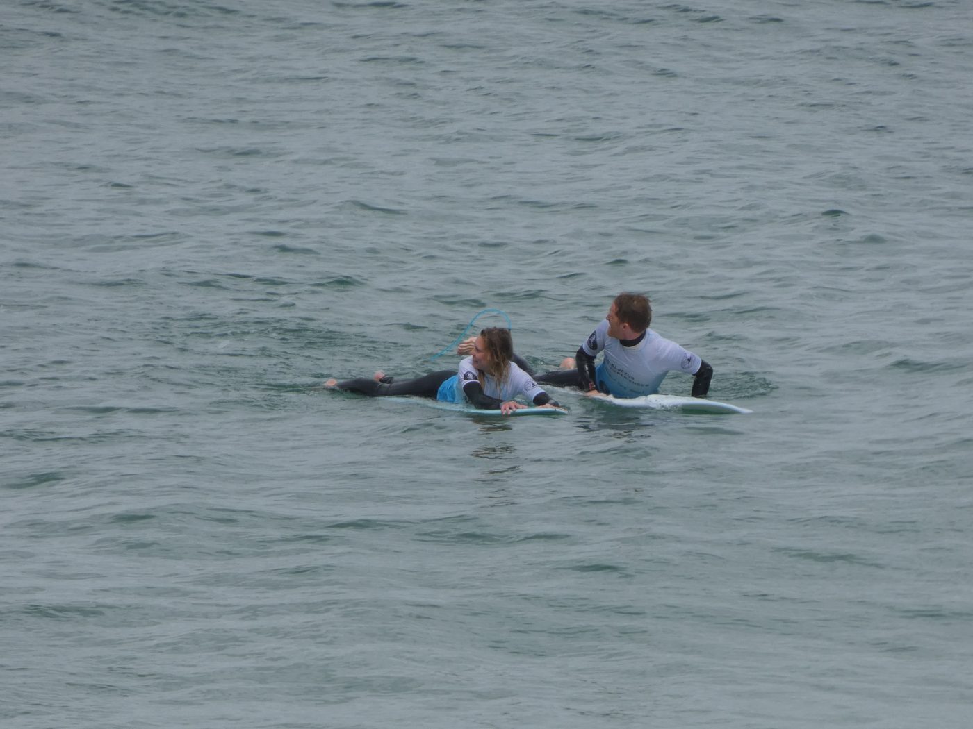 Vasco alongside a participant in the water, setting up a wave