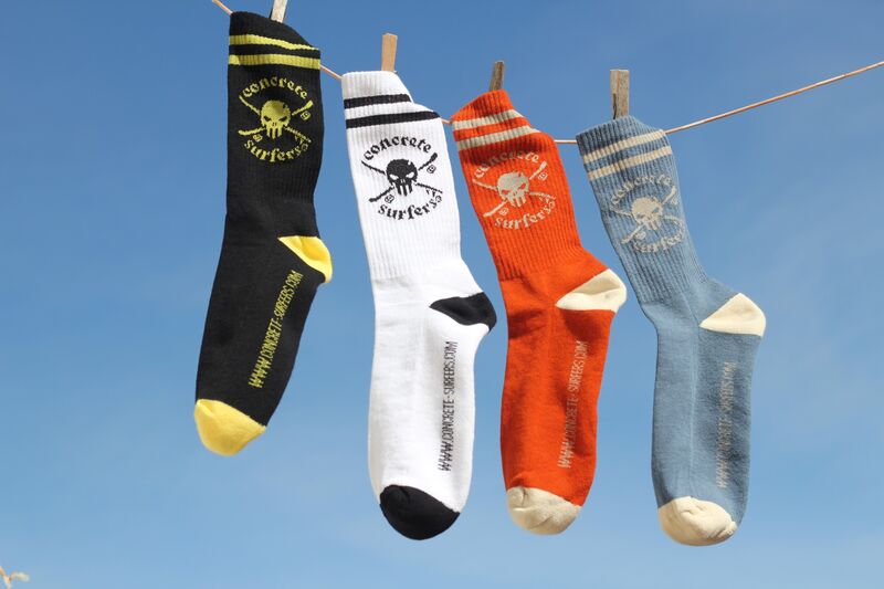 The four Concrete Surfers socks hanging on a line against a blue sky