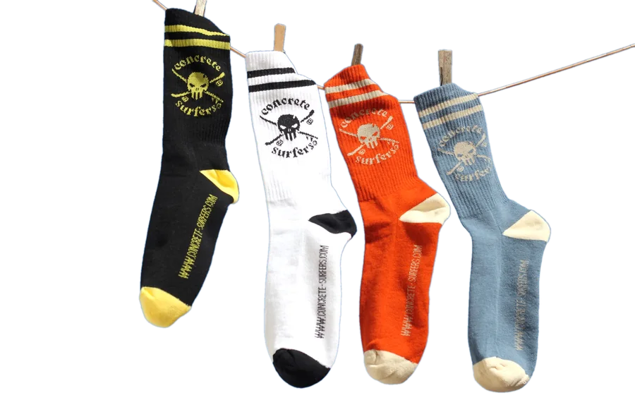 The four Concrete Surfers socks hanging on a line: Black & Yellow, White & Black, Terracota & Creme, Light Blue & Creme